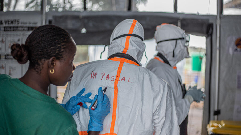 A health worker records a doctor's name on the back of their personal protective equipment before entering the Ebola treatment center in Rwampara to care for patients with Ebola virus disease, in Bunia, Ituri, eastern Democratic Republic of Congo, July 13, 2026.