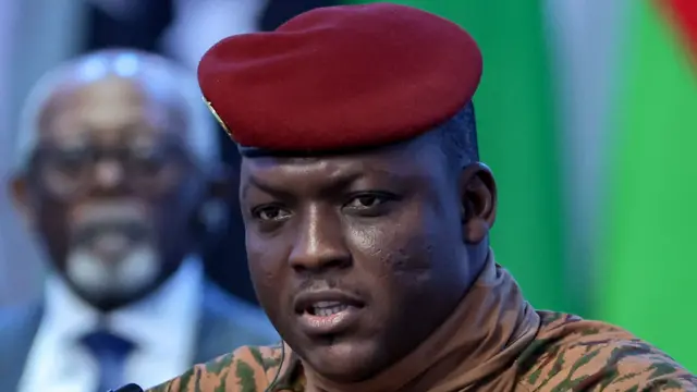 Close-up of Ibrahim Traoré in military attire with a red beret against a neutral background